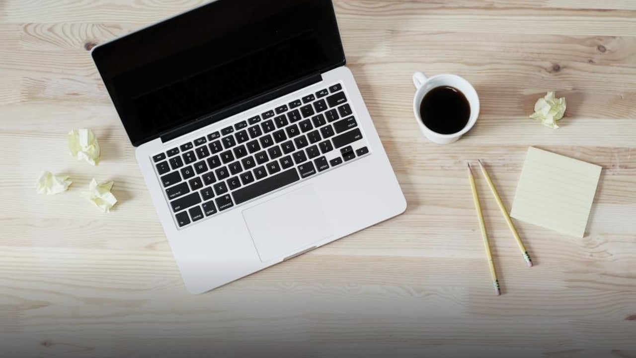 A laptop, coffee and sticky notes on a light desk